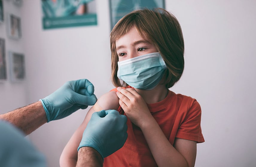 戴口罩的小女孩在接种疫苗后，医生给她贴创可贴
